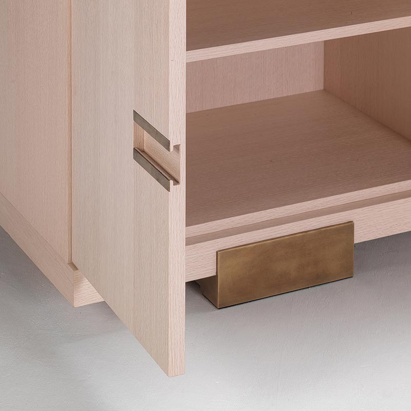 Bleached oak sideboard corner detail with patinated brass foot and inset handle