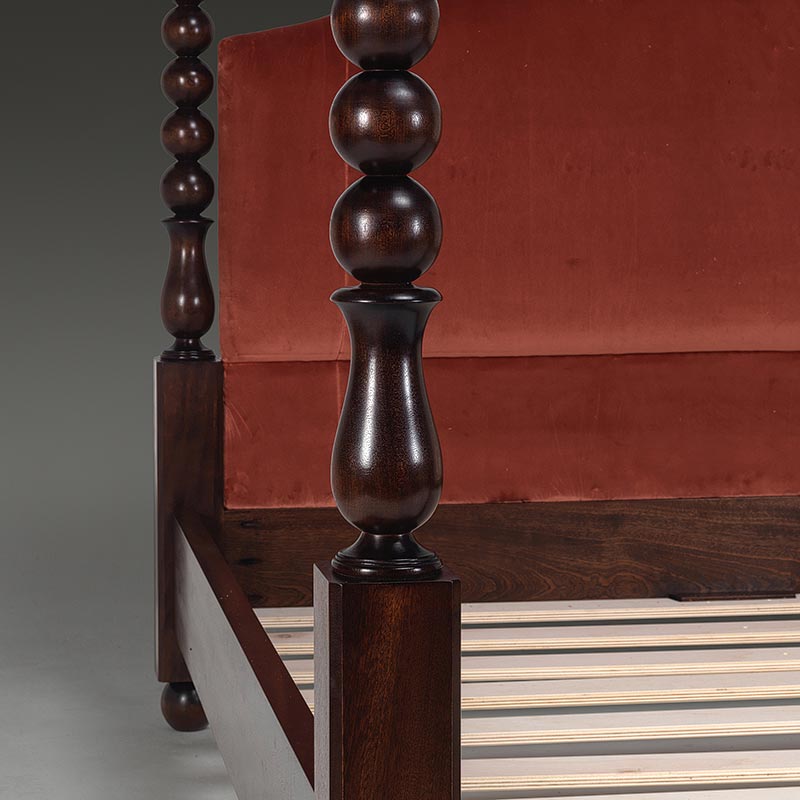Detail of bobbin four poster bed showing turned post and upholstered headboard