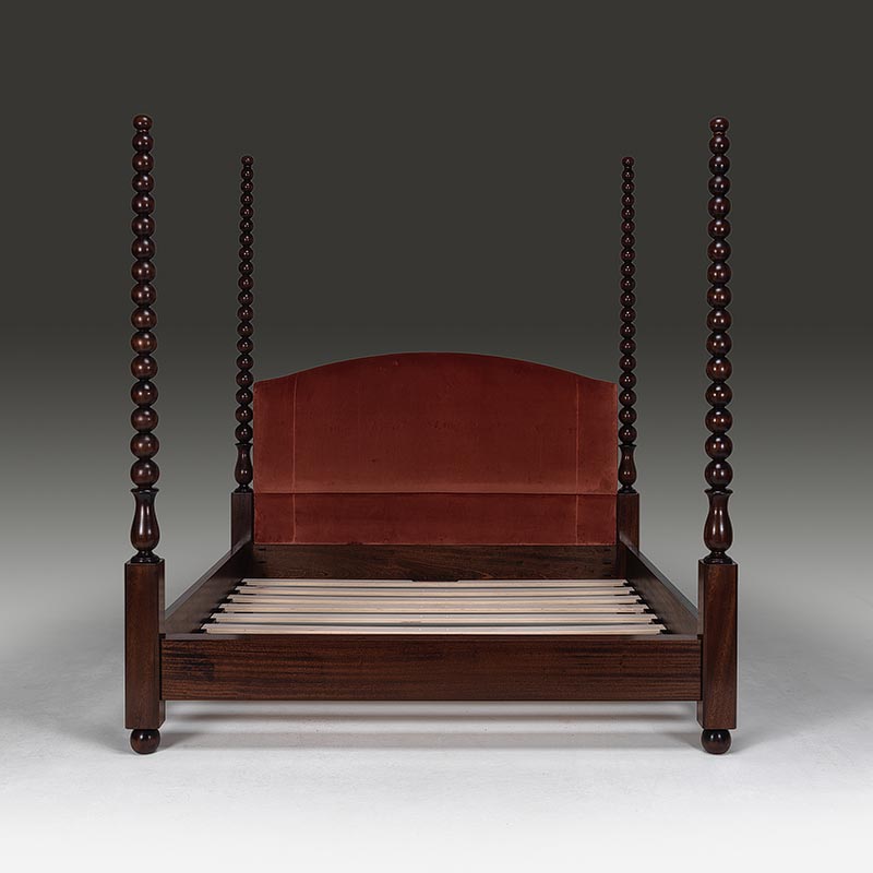 Front view of bobbin four poster bed with turned posts and upholstered headboard