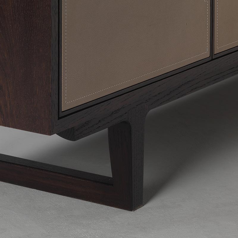 Detail of oak sideboard base and brass stand with leather panel doors