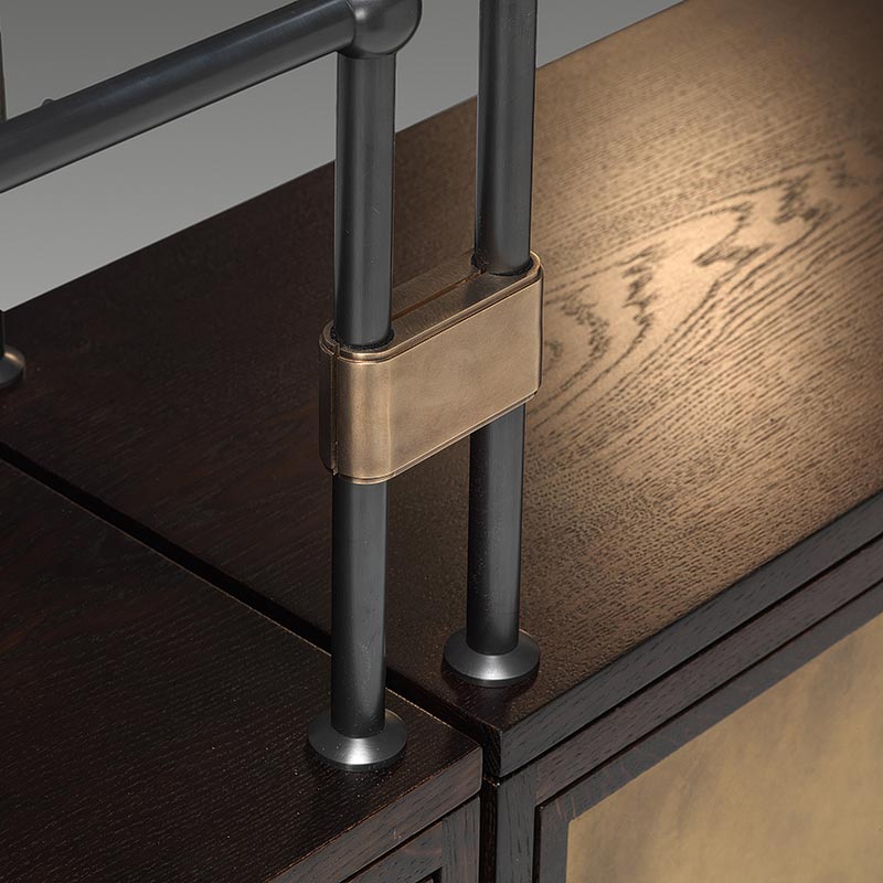 Detail of brass bracket and black metal shelving on oak credenza unit