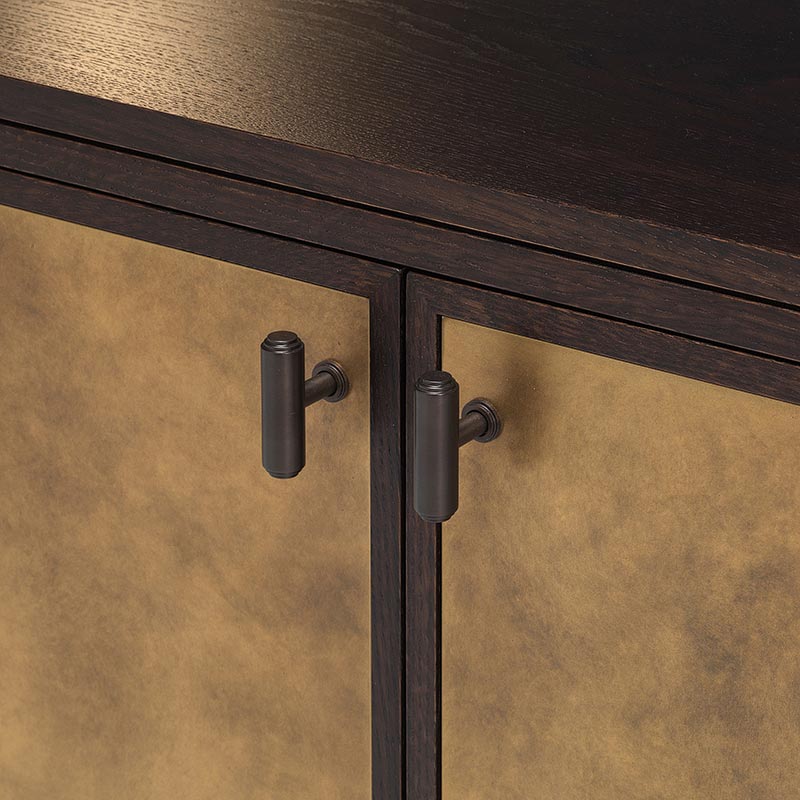 Close-up of oak credenza with brass inset doors and dark metal handles